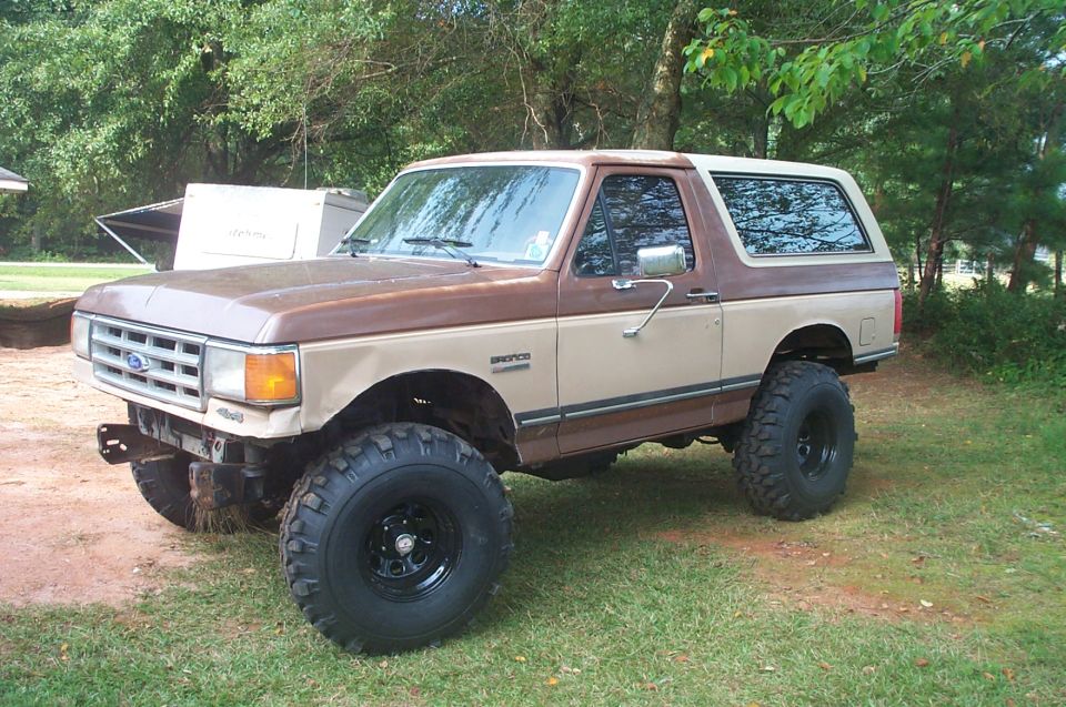 1987 Ford Bronco with body lift and large tires parked on grass
