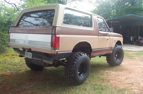1987 Ford Bronco - This lifted 1987 Ford Bronco is shown from the rear, with a two-tone brown and tan paint scheme.