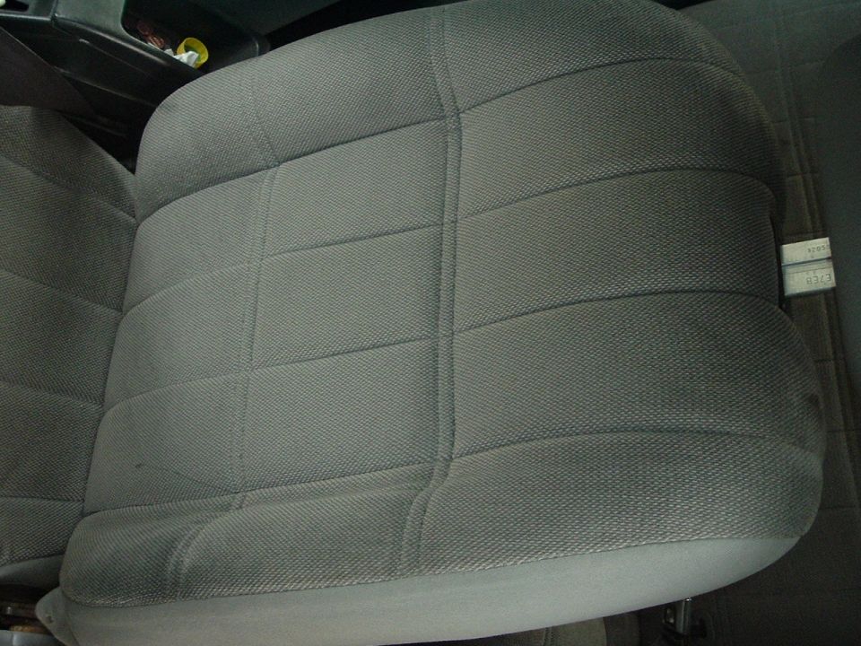Gray fabric car seat with horizontal stitching detail. A small white label with text is visible on the right side