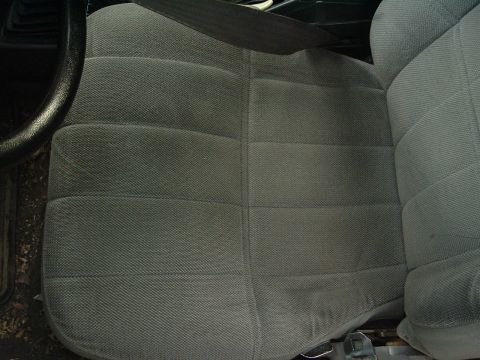 1989 Ford Escort - The interior driver's seat and seatbelt are visible in this close-up shot.