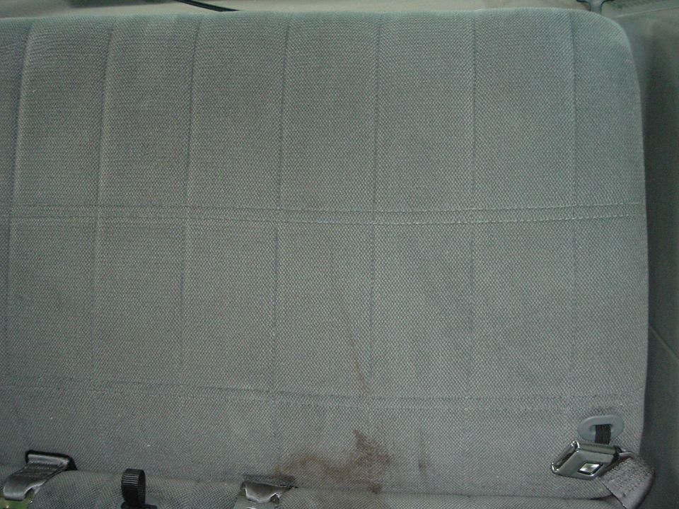 Gray fabric car seat upholstery with vertical stitching and some stains near the bottom