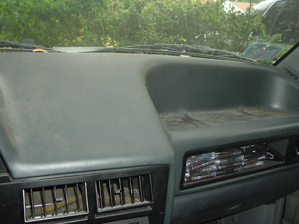 Dashboard of a 1989 Ford Escort, showing air vents and a sticker on the windshield
