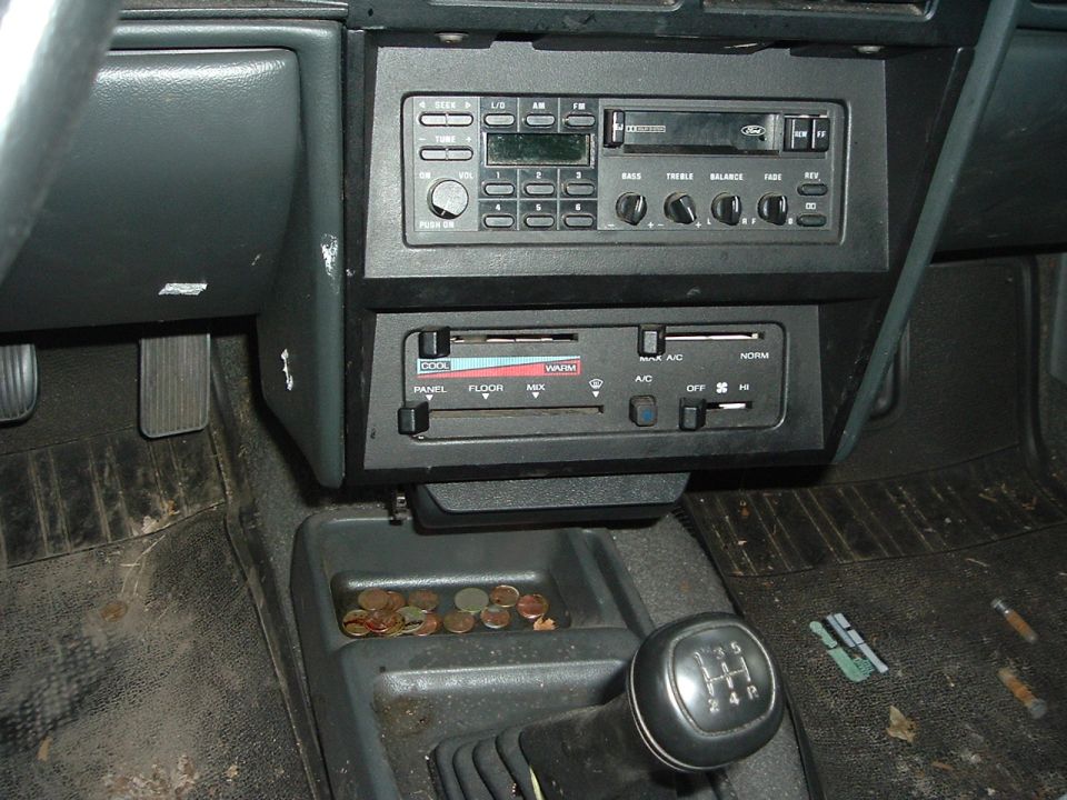 Interior view of a car's center console with a manual shifter, radio, and climate controls