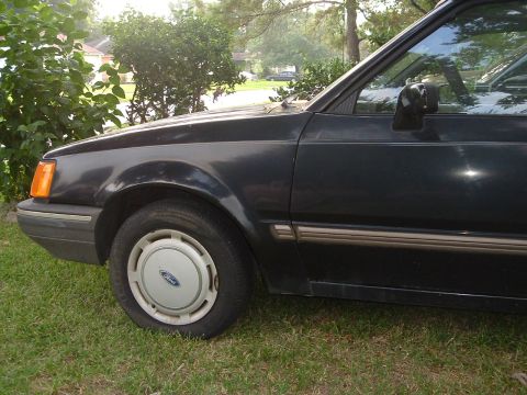 1989 Ford Escort - Side view of a 1989 Ford Escort, showing its dark blue paint and wheel cover.