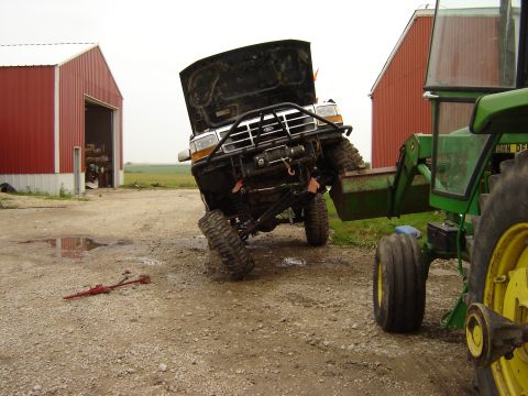 1992 Ford Bronco - A 1992 Ford Bronco is being lifted by a John Deere tractor loader on a farm.