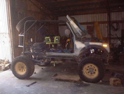 1989 Ford Bronco - Modified off-road vehicle in a garage with a roll cage and exposed interior.