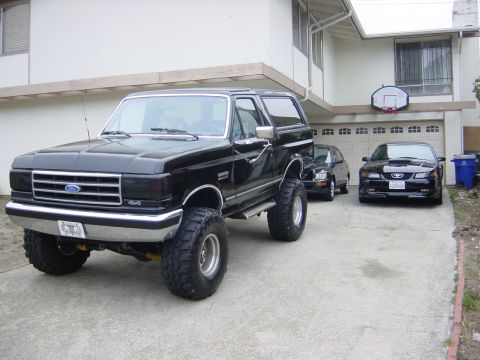 1990 Ford Bronco - This lifted 1990 Ford Bronco is parked in a driveway with two other vehicles.