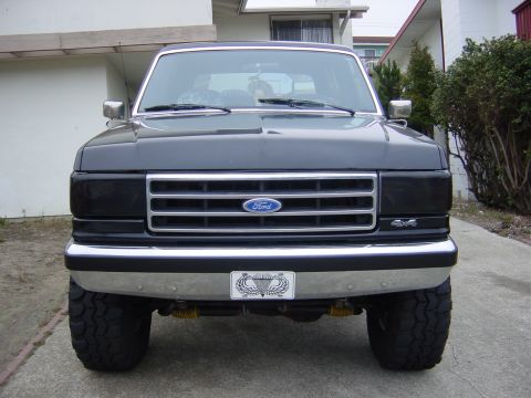 1990 Ford Bronco - Front view of a dark gray 1990 Ford Bronco with a chrome grille and aftermarket bumper.