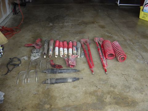1990 Ford Bronco - Various suspension parts, such as shocks and springs, are arranged on a garage floor.
