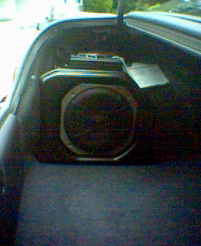 2004 Dodge SRT-4 - Subwoofer installed in the trunk of a vehicle. Watermark indicates Supermotors.