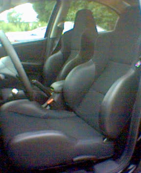 2004 Dodge SRT-4 - The interior of a car is shown, with a focus on the front seats and dashboard area. A Supermotors logo is visible at the bottom.