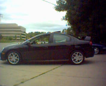 2004 Dodge SRT-4 - A black 2004 Dodge SRT-4 sedan is parked outdoors, showing its side profile and rear spoiler.