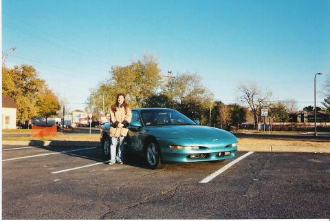 1993 Ford Probe - A teal 1993 Ford Probe is parked in a lot on a clear day, with a woman standing next to the driver's side door.