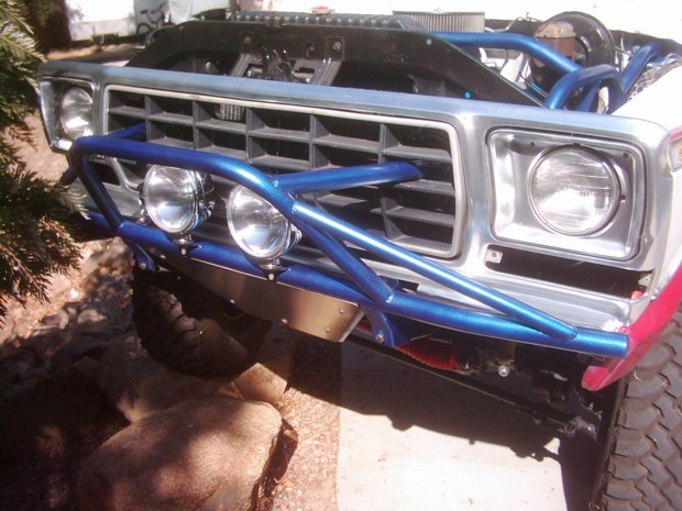 Blue tube prerunner bumper with round driving lights on a lifted Ford 4x4 grille