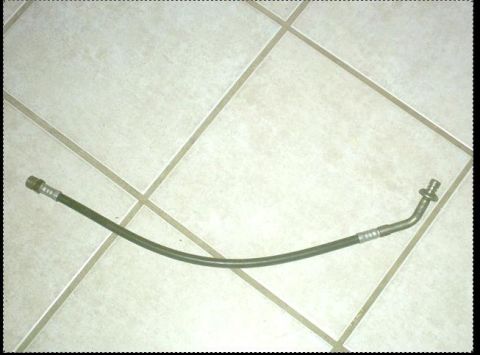 1992 Ford Bronco - A single brake hose with metal fittings is shown against a tiled background.