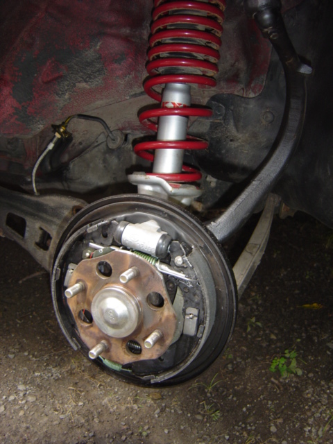 1998 Ford Taurus - Close-up of a vehicle's rear drum brake assembly and a red coilover shock.