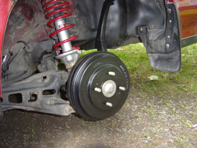 Rear drum brake assembly with red coilover shock absorber and black mud flap