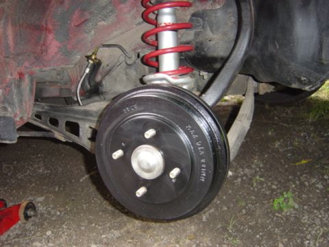 1998 Ford Taurus - Close-up of a rear drum brake assembly, likely from a sedan or coupe, with a red coilover shock visible.
