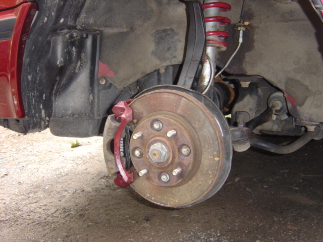 Close-up of a car's front wheel, brake rotor, caliper, and suspension components