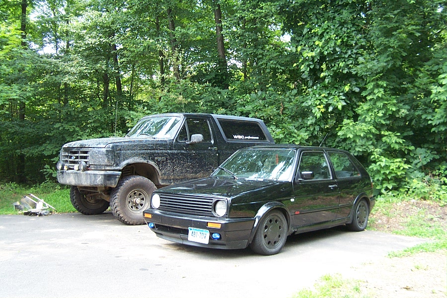 Black 1992 Ford Bronco and black Volkswagen Golf parked outdoors