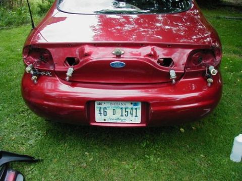 1997 Ford Taurus - Rear view of a 1997 Ford Taurus with both tail lights removed, showing exposed bulbs and wiring.