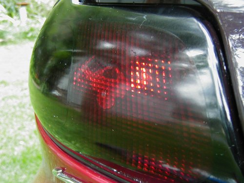 Close-up of a dark-tinted car tail light with red bulbs visible