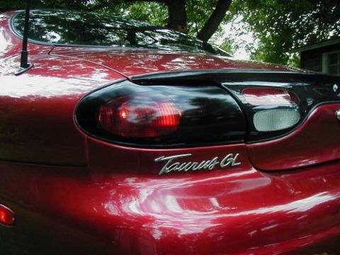1997 Ford Taurus - Close-up of a red car's rear, its tail lights and a 'Taurus GL' emblem.