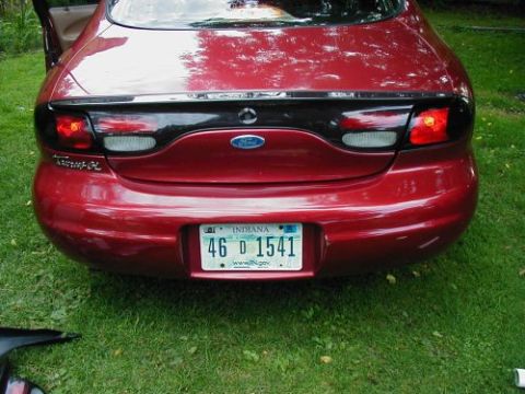 1997 Ford Taurus - The rear of a red 1997 Ford Taurus is shown with a black accent panel between the taillights.