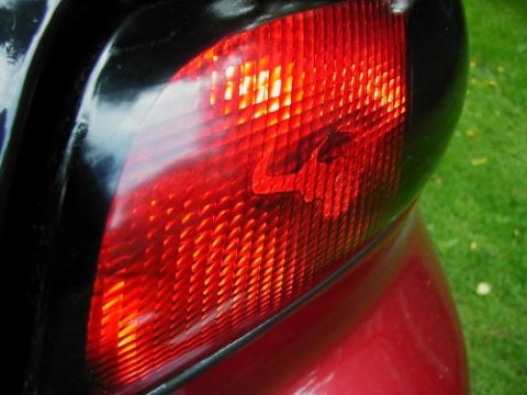 1997 Ford Taurus - Close-up of the red tail light assembly on a 1997 Ford Taurus, showing the textured lens and black housing.