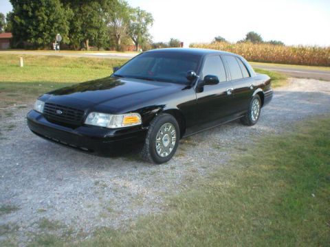 1987 Ford Crown Victoria LTD - This black sedan is captured from a 3/4 front angle, parked on a gravel surface next to a grassy area.