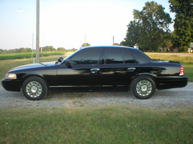 Black sedan with tinted windows parked on a gravel road