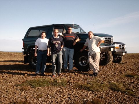1996 Ford Bronco - A group of men pose with a large, lifted SUV in a rocky, outdoor landscape under a clear sky.