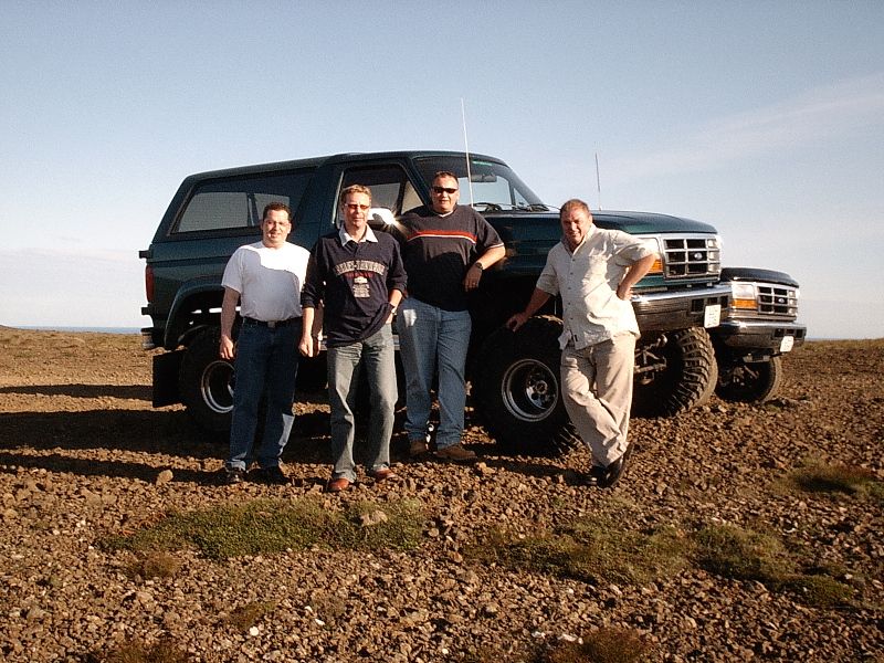 Four men posed in front of a lifted green Ford Bronco SUV on rocky ground