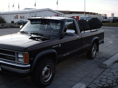 1996 Ford Bronco - 1990 Dodge Dakota pickup truck with spare tires loaded in the bed, parked outdoors.
