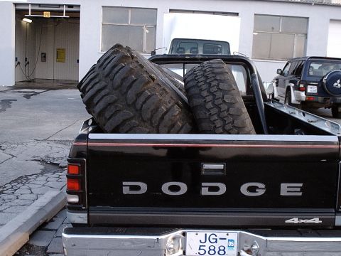 1996 Ford Bronco - A Dodge pickup truck carries oversized tires, with an SUV visible in the background.