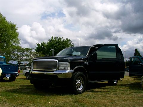 2000 Ford Excursion - Black Ford Excursion parked on grass with doors open, another truck is visible to the left.