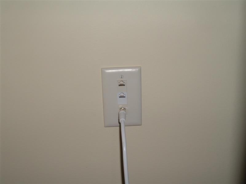 White wall plate with two RJ45 jacks and a coax connector with white cable attached