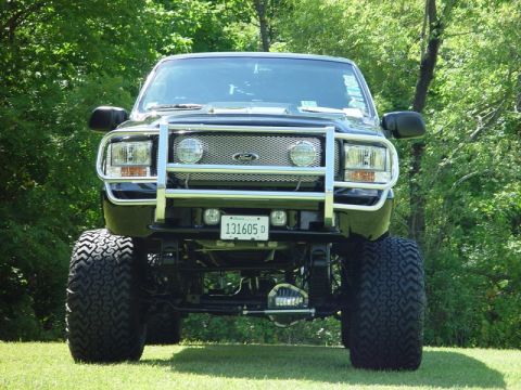 2001 Ford Excursion - Lifted 2001 Ford Excursion with custom grille guard and off-road tires parked outdoors.
