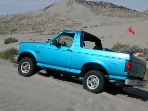 1994 Ford Bronco - This blue 1994 Ford Bronco navigates sandy terrain, its removable top exposing the interior to the open air.