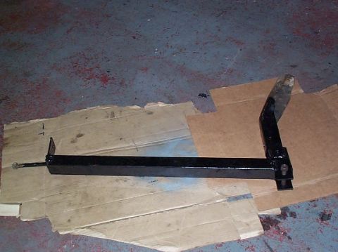 1978 Ford Bronco - A black metal bracket lies on cardboard on a workshop floor.