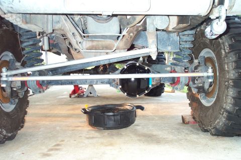1995 Ford Bronco - View under the front of a lifted 4x4 showing a solid front axle with a freshly painted black differential cover, silver crossover steering…