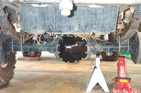 1995 Ford Bronco - View straight under the rear of a lifted truck showing the solid rear axle with a freshly painted gloss-black differential cover, leaf spri…