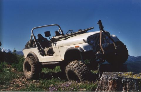1990 Ford Bronco - White Jeep CJ-7 navigates an off-road trail with a large tire placed on a tree stump.