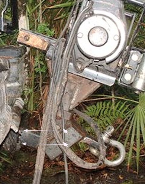 1993 Ford Bronco - A close-up view of a vehicle's winch and tow hook assembly, partially obscured by foliage.