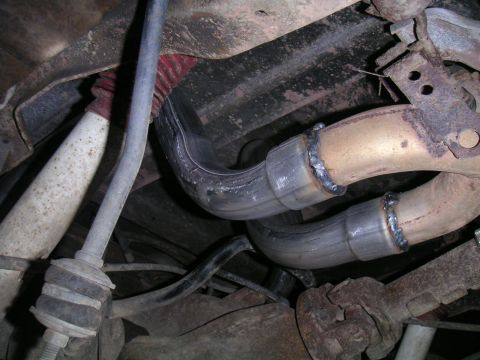 1994 Ford Bronco - Undercarriage shot of a dual exhaust with two new stainless-look pipe sections welded to the older catalytic-converter pipes, the fresh wel…
