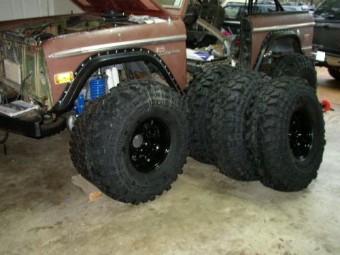 1995 Ford Bronco - A 1974 Ford Bronco is shown with its front fender exposed, revealing suspension and four large off-road tires.