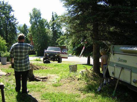 1985 Ford Bronco - A man waves while a red and white pickup truck is parked in a grassy yard with a trailer nearby.
