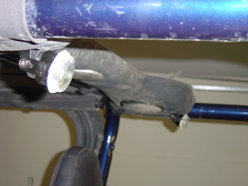 Round chrome accessory light bracket-mounted to a dark blue roll bar, seen up close from inside