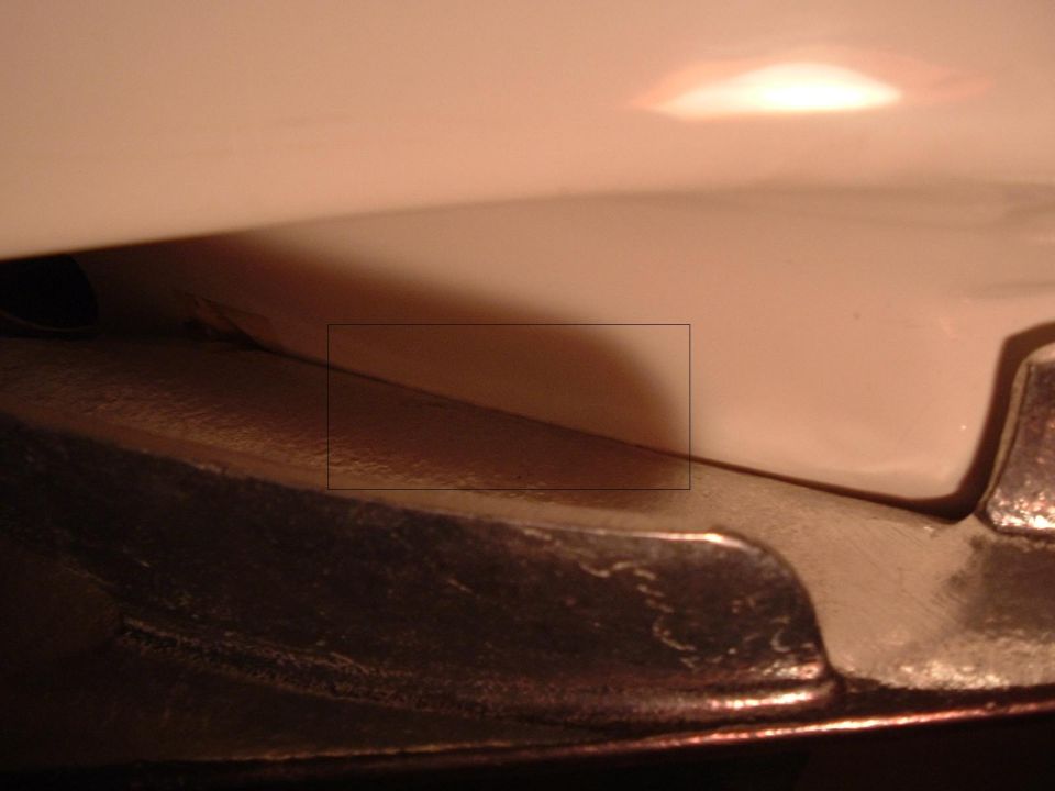 Close-up of a dark, textured car part against a smooth, light-colored surface