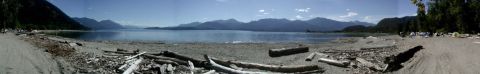 1993 Ford Bronco - A panoramic view of a beach campsite with a lake and mountains under a clear blue sky.